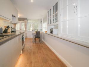 a kitchen with white cabinets and a long counter at Woodland Lodge in Grange Over Sands
