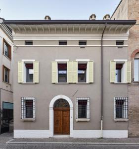 um edifício com janelas amarelas fechadas e uma porta em Casa Gugù em Ravenna