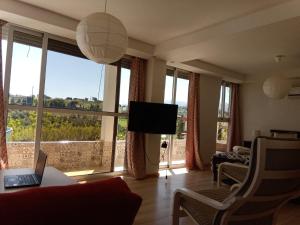 a living room with a couch and a tv and windows at Appart Hôtel Signature in Taza