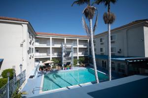 a view of a hotel with a swimming pool and palm trees at Brookhurst Plaza Inn in Anaheim