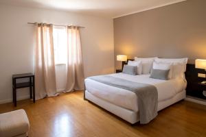 a bedroom with a large white bed and a window at Vila Bicuda Resort in Cascais