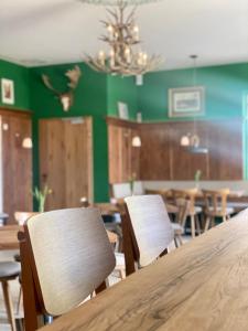 a dining room with green walls and wooden tables and chairs at Hotel Waitzingers in Landsberg am Lech