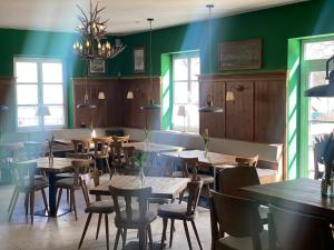 a restaurant with tables and chairs and green walls at Hotel Waitzingers in Landsberg am Lech