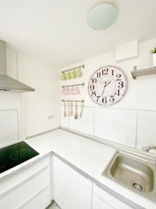 cocina blanca con reloj y fregadero en Loft with Rooftop and Garage, en Budapest