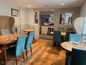 a restaurant with wooden tables and blue chairs at The Dartmoor Inn at Lydford in Lydford
