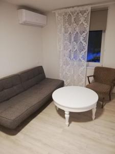 uma sala de estar com um sofá e uma mesa em Vėjo 16 em Biržai