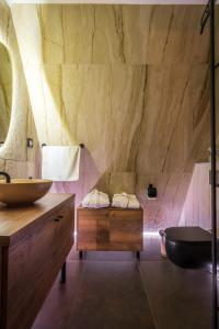 y baño con pared de piedra, lavabo y bañera. en Masarotto Luxury Chalet #2 en Belgrado