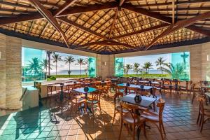a restaurant with tables and chairs and palm trees at Quinta do Sol Praia Hotel in Porto Seguro