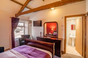 1 dormitorio con cama, espejo y lavamanos en The Village Inn, en Longframlington