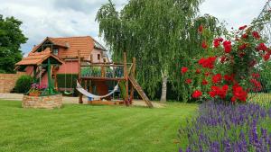 a house with a hammock in a yard with flowers at Penzion Na Lednické in Hlohovec