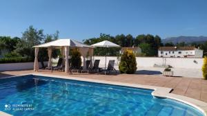 - une piscine avec des chaises et des parasols sur une terrasse dans l'établissement Chalet Embalse Bermejales, à Arenas del Rey
