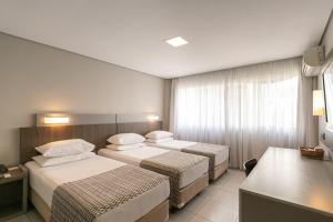 a hotel room with three beds and a window at Saint Emilion by Atlantica in Curitiba
