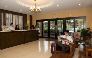 un hombre sentado en una silla en el vestíbulo de un hotel con sus documentos en Hotel Vistaria, en Johor Bahru
