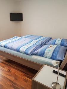 uma cama com um edredão azul e uma mesa em Ferienwohnung- SARAH em Hahnstätten