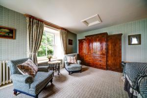 a bedroom with two beds and chairs and a window at High Force Hotel in Newbiggin