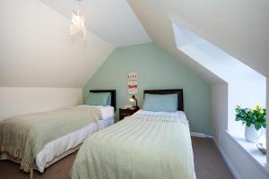 Cette chambre mansardée comprend 2 lits et une fenêtre. dans l'établissement Finest Retreats - Ellie-Jo Cottage, à Gardenstown