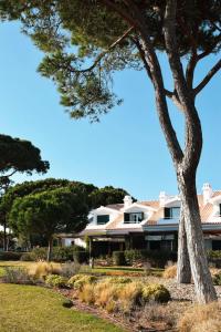 uma grande casa branca com uma árvore em primeiro plano em Vila Bicuda Resort em Cascais