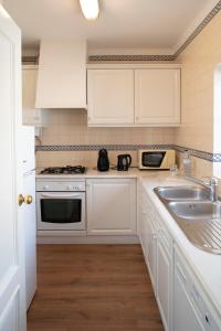 a kitchen with white cabinets and a sink at Vila Bicuda Resort in Cascais