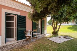 a house with a table and a chair next to a tree at Vila Bicuda Resort in Cascais