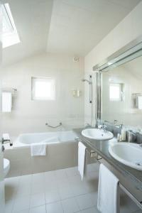 a white bathroom with two sinks and a bath tub at Vila Bicuda Resort in Cascais