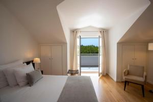 a bedroom with a large white bed and a window at Vila Bicuda Resort in Cascais