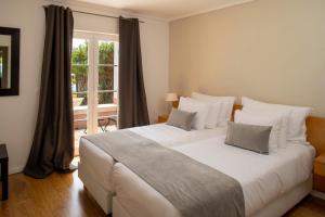 a large white bed in a room with a window at Vila Bicuda Resort in Cascais