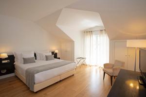 a bedroom with a large white bed and a table at Vila Bicuda Resort in Cascais