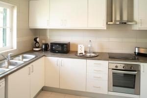 a kitchen with white cabinets and a sink and a microwave at Vila Bicuda Resort in Cascais