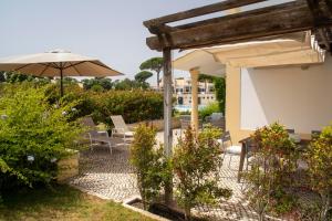 a patio with an umbrella and chairs and tables at Vila Bicuda Resort in Cascais