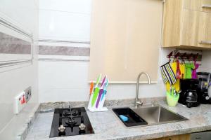 a kitchen counter with a sink and a stove at GAZANIA CLASSIC SUITE, RHODABODE APT. in Abuja