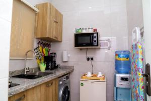 uma pequena cozinha com um lavatório e um micro-ondas em GAZANIA CLASSIC SUITE, RHODABODE APT. em Abuja