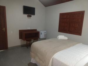 a bedroom with a bed and a desk and a television at Pousada Flor Nativa in Brejetuba +9 photos