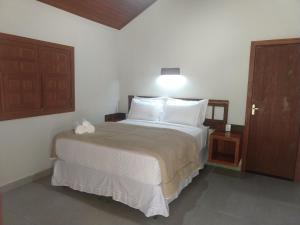 a bedroom with a large bed with white pillows at Pousada Flor Nativa in Brejetuba