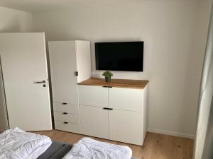 1 dormitorio con armario blanco y TV. en Ferienwohnung Hohe Lith, en Cuxhaven