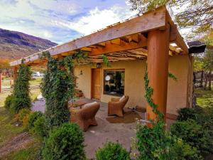 a house with a pergola and chairs in a yard at Hacienda Tres Lagos in Aldana