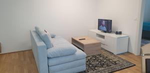a living room with a blue couch and a tv at Exquisit Apartment Simmering in Vienna