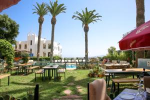 un patio con tavoli, palme e piscina di Hôtel Rembrandt a Tangeri