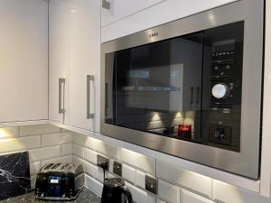 a kitchen with a large microwave above a counter at Walsingham House - Modern 2 Bed - Driveway Parking - Marvello Properties in Norwich