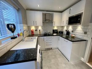 a kitchen with white cabinets and black counter tops at Walsingham House - Modern 2 Bed - Driveway Parking - Marvello Properties in Norwich