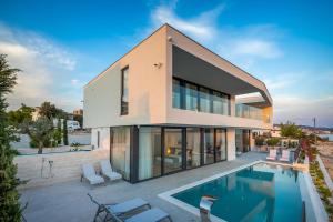 a house with a swimming pool in front of it at Animare Villas in Rogoznica