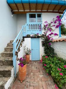 Hotel Casa Boutique Villa de Leyva في فيلا دي ليفا: منزل فيه باب ازرق وبعض الزهور