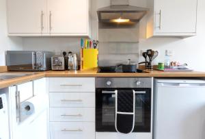 uma cozinha com armários brancos e um forno preto em City Haven Preston Apartments em Preston