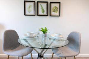 szklany stół z dwoma krzesłami i trzema oprawionymi zdjęciami w obiekcie City Haven Preston Apartments w mieście Preston
