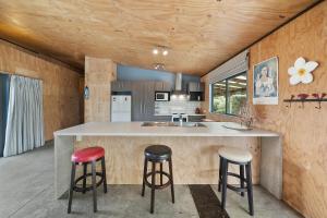 una cocina con una gran isla con taburetes en Tranquilo - Waikawa Beach Holiday Home, en Manakau