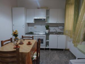 レトイアンニにあるCasa Vacanze Nonna Teresaのキッチン(白いキャビネット、テーブル、シンク付)
