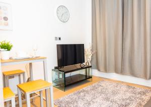 a living room with a flat screen tv and a table at Absolute Stays at The Ziggurat - St Albans-High Street- Near Luton Airport - St Albans Abbey Train station -Close to London- Harry Potter World - The Odyssey Cinema-Contractors -London Road-Business-Leisure in Saint Albans