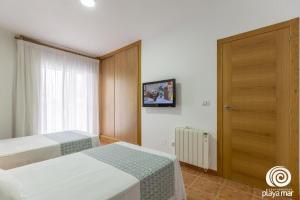モンタルボにあるApartamentos Turísticos Playa Mar Iのベッド2台とドアが備わるホテルルームです。