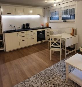 une cuisine avec des placards blancs et une table dans l'établissement Am Borgwallsee 2, à Steinhagen