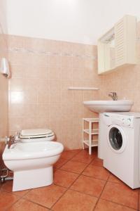 a bathroom with a toilet and a sink and a washing machine at Appartamenti Ideal in Isola Rossa