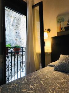 セテニル・デ・ラス・ボデガスにあるCasa Bajo la Rocaのベッドルーム1室(ベッド1台付)、バルコニーへのドアが備わります。